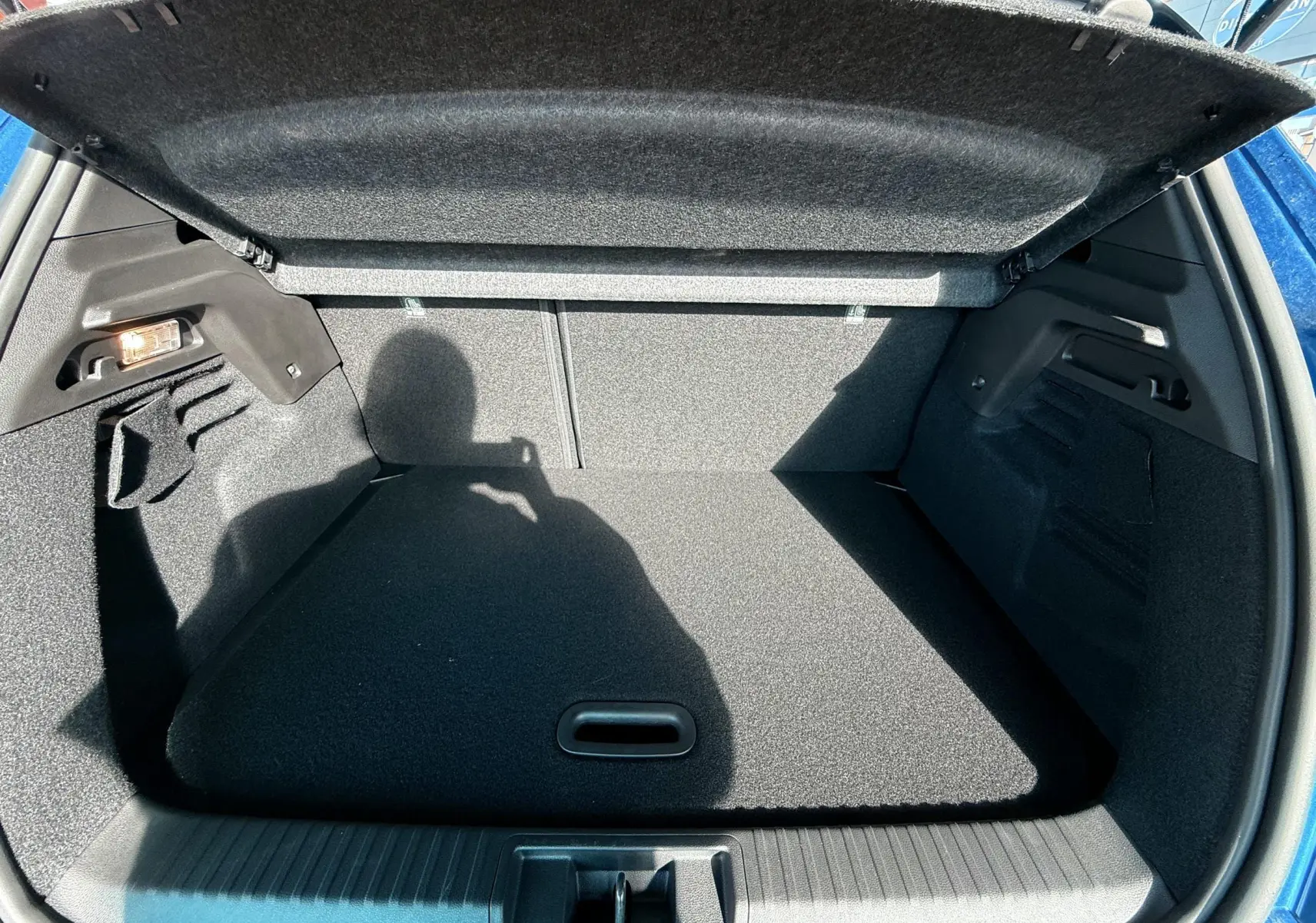 Coffre ouvert du Renault Captur E-Tech hybride 2025 en bleu Iron Metal avec toit noir, vue arrière intérieure.