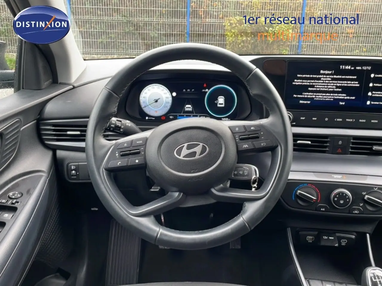 Vue intérieure centrée sur le volant cuir et le tableau de bord numérique de la Hyundai i20 noire Phantom Metal 2025.