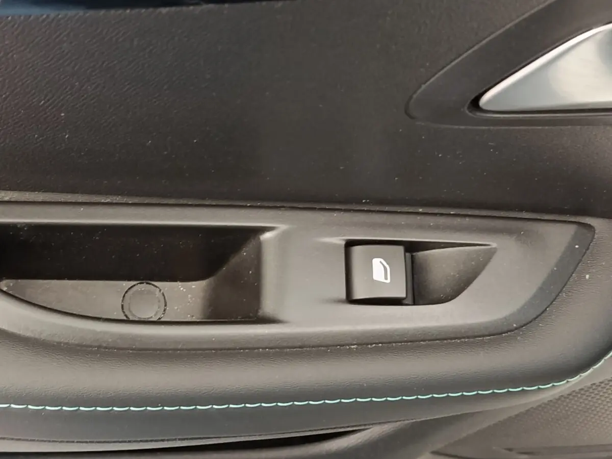Gros plan sur la commande de lève-vitre côté porte intérieure d’une Peugeot 208 blanche, finition Allure Business.