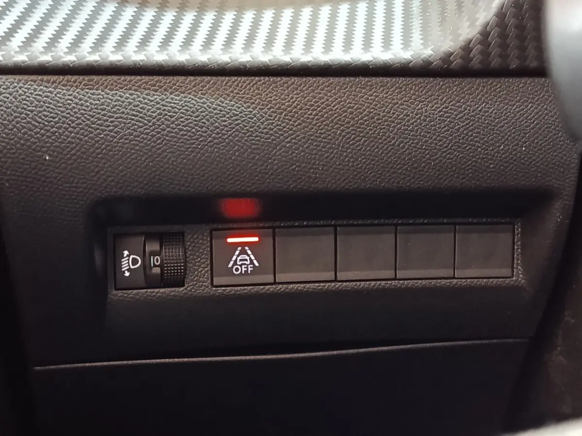 Détail intérieur du tableau de bord de la Peugeot 208 blanc, montrant les commandes d’éclairage et d’aide à la conduite.