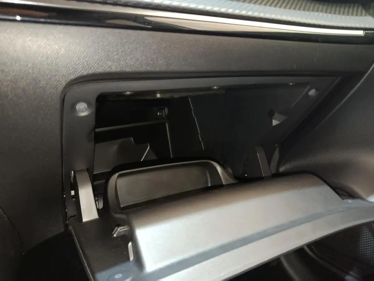 Vue rapprochée de la boîte à gants ouverte côté passager du Peugeot 208 blanc, intérieur noir.