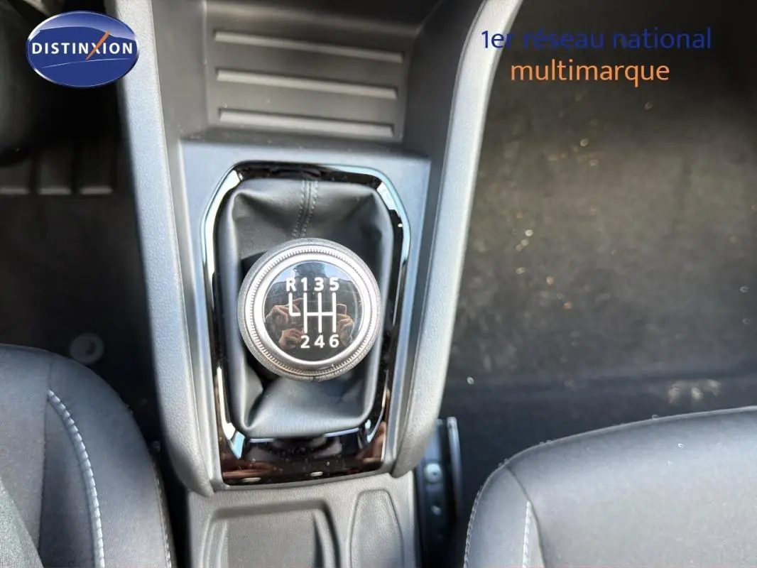 Gros plan sur le levier de vitesse manuel de la Renault Clio gris foncé, intérieur avec sièges tissu noirs.