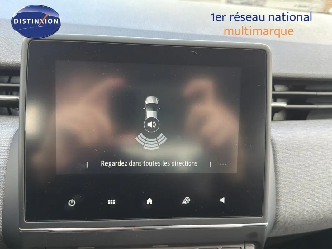 Écran tactile intérieur de la Renault Clio gris foncé 2026 affichant l'aide au stationnement avec message de vigilance.