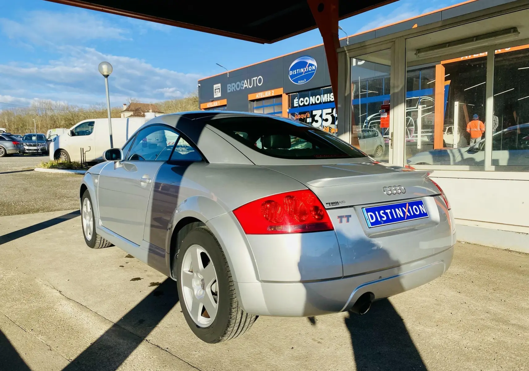 Audi TT Coupé gris vu en 3/4 arrière droit, mettant en valeur son design compact et son aileron arrière intégré.