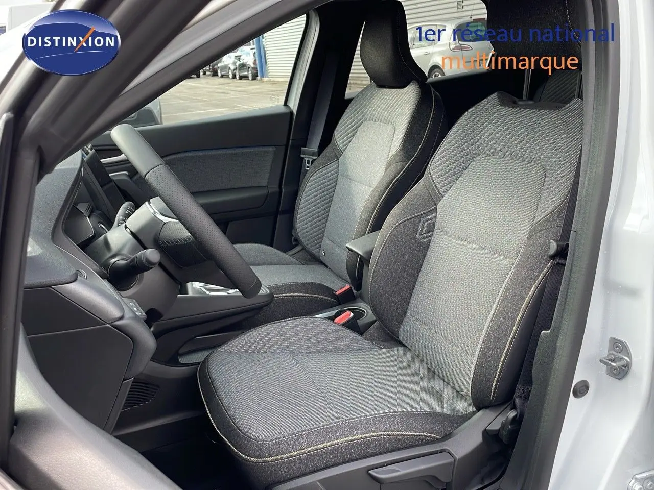 Intérieur côté conducteur du Renault Captur E-Tech hybride 2025 avec sièges tissu gris et volant noir, porte blanche ouverte.