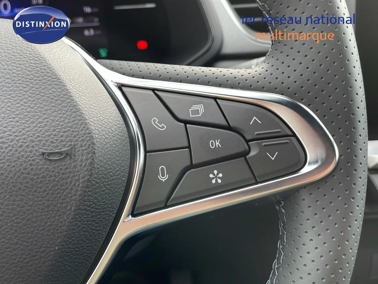 Gros plan sur les commandes au volant en cuir perforé du Renault Captur blanc nacré 2025, version hybride E-Tech.