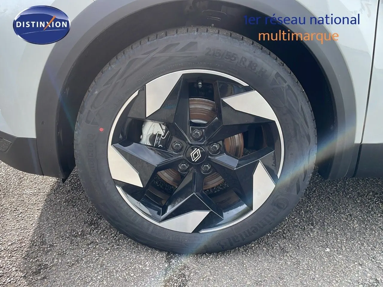 Gros plan sur la roue avant droite du Renault Captur blanc nacré avec jante noire et argentée au design moderne.