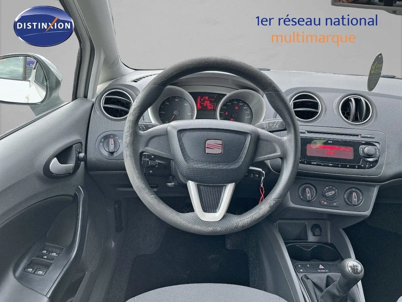 Vue intérieure centrée sur le volant et tableau de bord d'une SEAT Ibiza blanche 1.6 TDI 90CH STYLE de 2010 avec boîte manuelle.