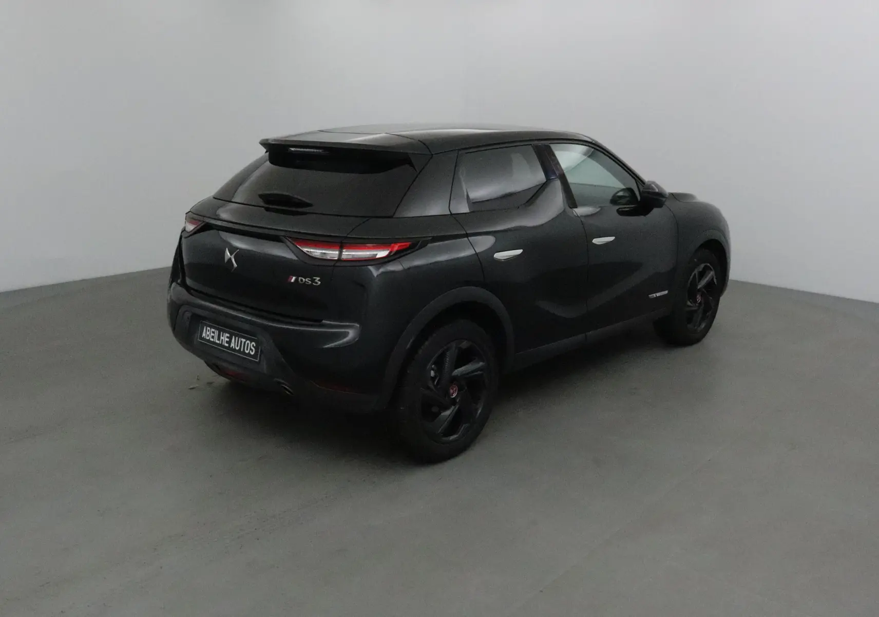 Vue 3/4 arrière droite d'un DS3 Crossback noir avec feux arrière LED et jantes noires dans un studio.