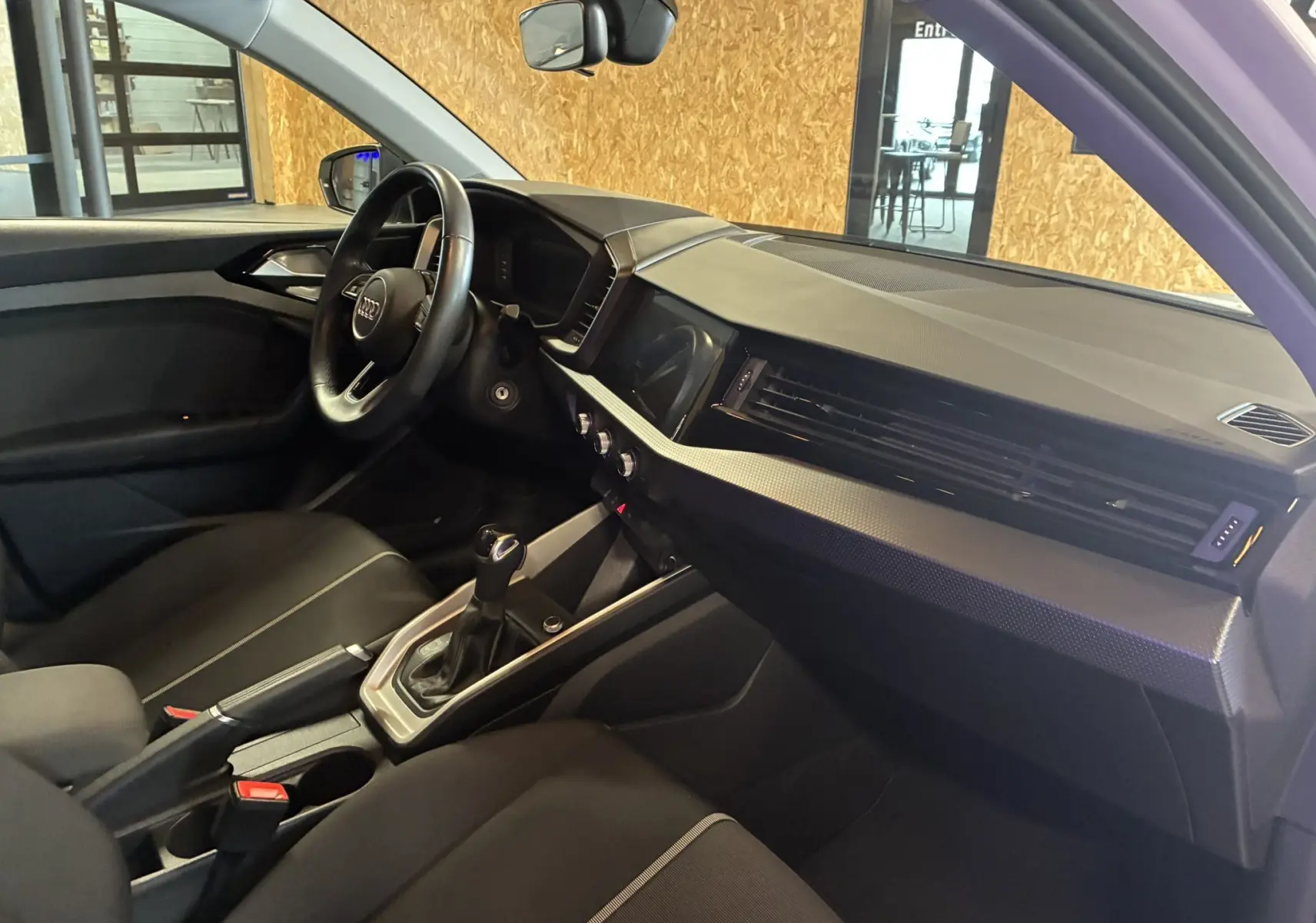 Intérieur noir de l'Audi A1 2022 vu côté conducteur, avec volant cuir multifonctions et console centrale moderne.