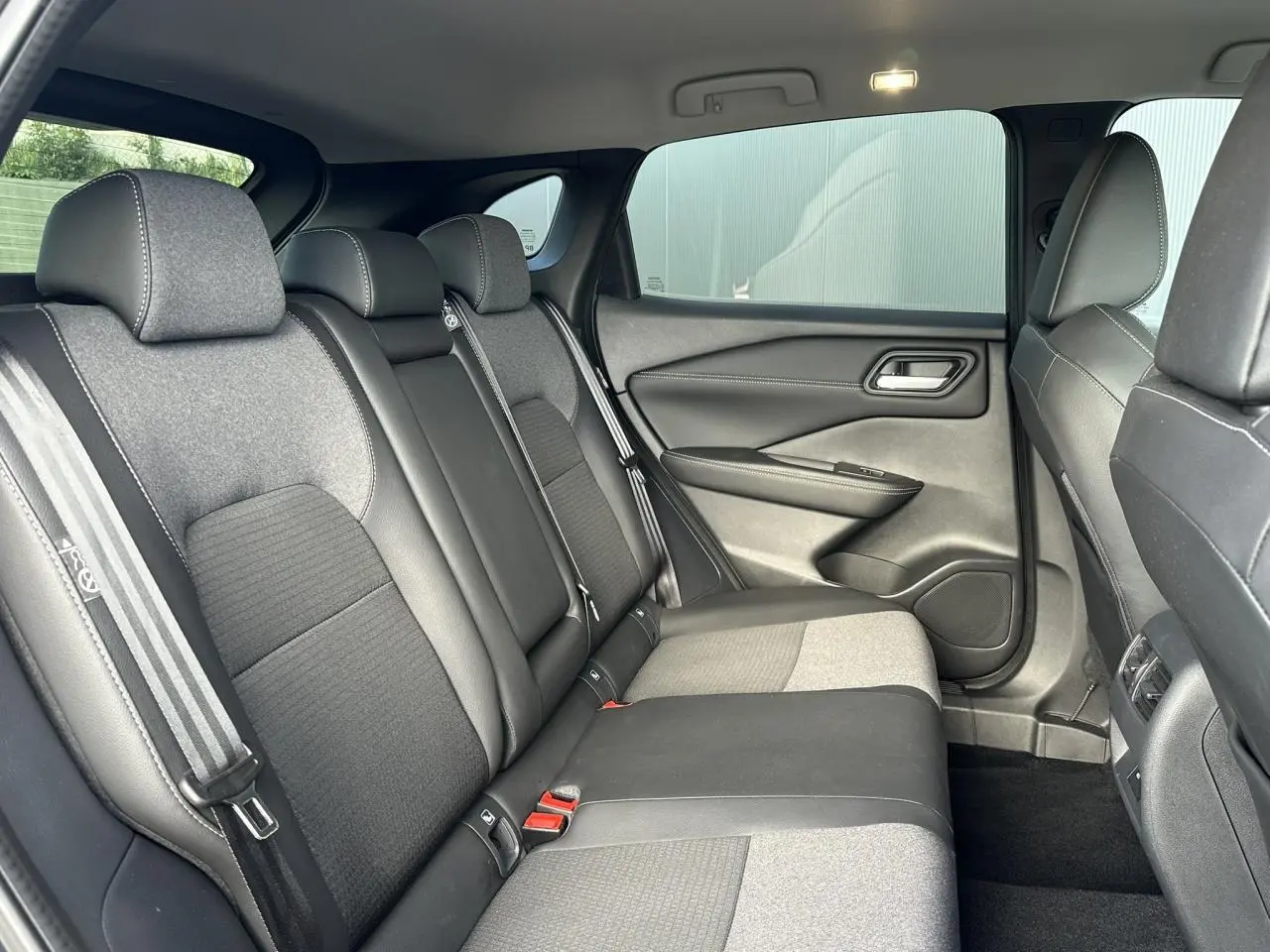 Vue latérale droite de l’habitacle arrière du Nissan Qashqai 2025 avec sellerie mixte tissu et TEP noir.