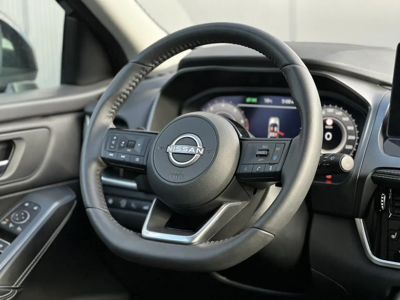 Vue rapprochée du volant cuir noir du Nissan Qashqai 2025 avec commandes intégrées et tableau de bord numérique.