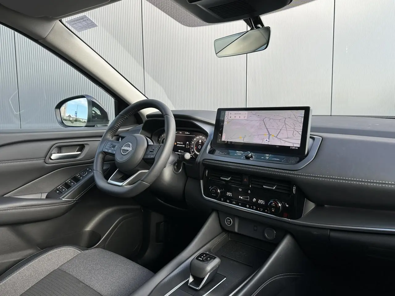 Vue intérieure côté conducteur du Nissan Qashqai 2025, tableau de bord noir avec écran tactile et volant cuir.