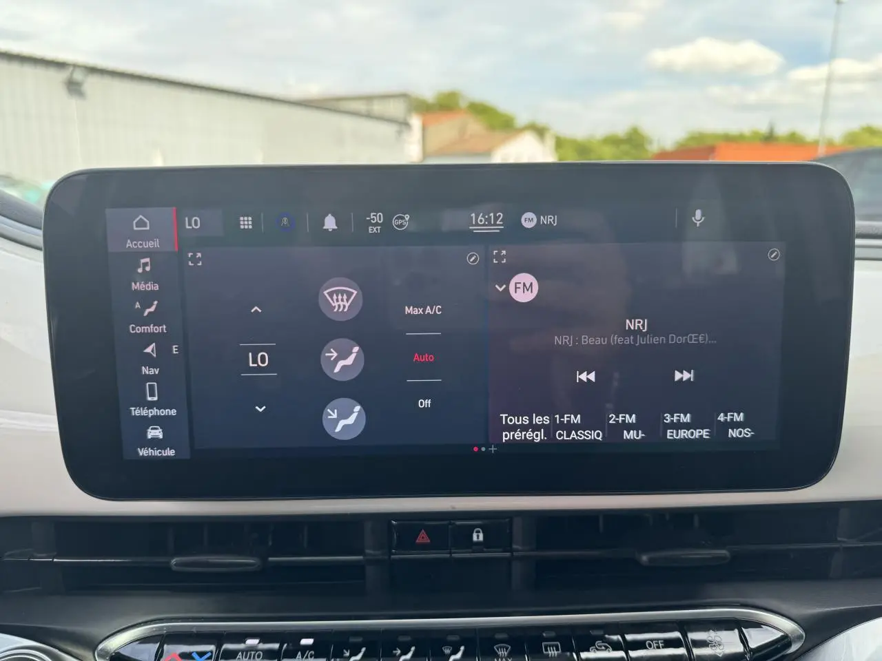 Écran tactile central de la Fiat 500 électrique 2022 affichant la climatisation et la radio FM NRJ.
