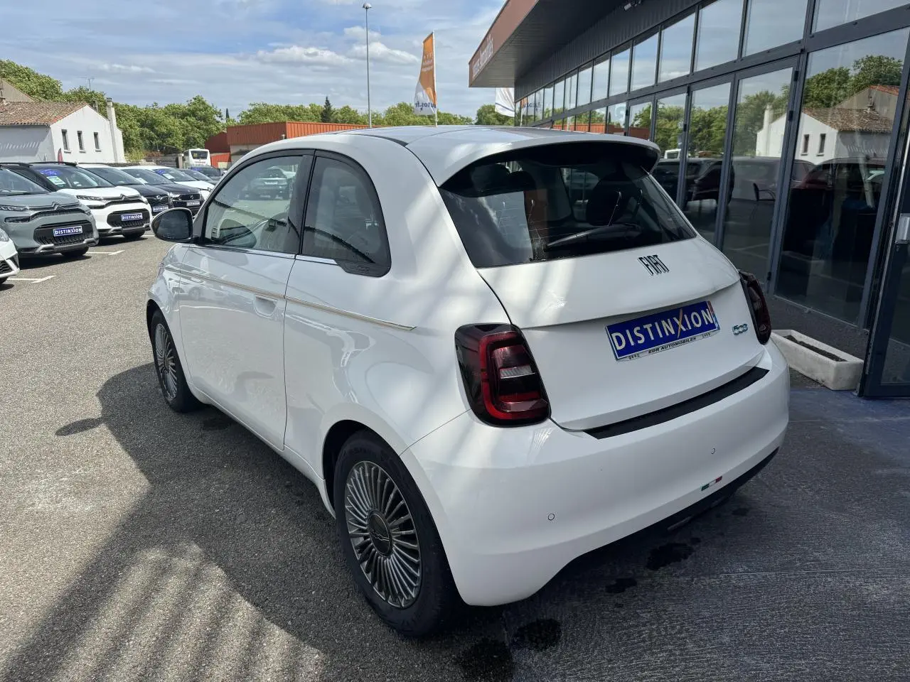 Vue 3/4 arrière droite d'une Fiat 500 électrique blanche avec jantes alliage 16'' et toit panoramique.