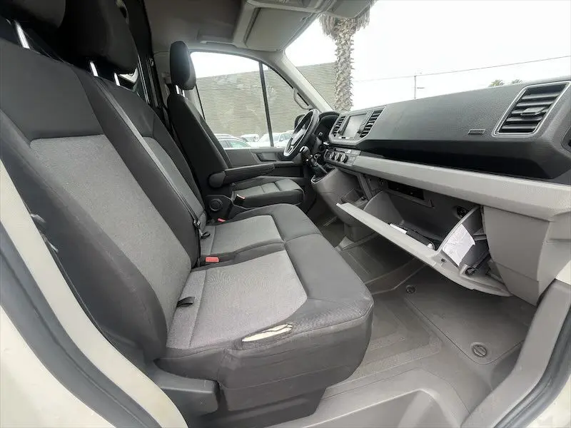 Intérieur du Volkswagen Crafter Fourgon blanc 2019, vue latérale côté passager avec sièges gris et boîte à gants ouverte.