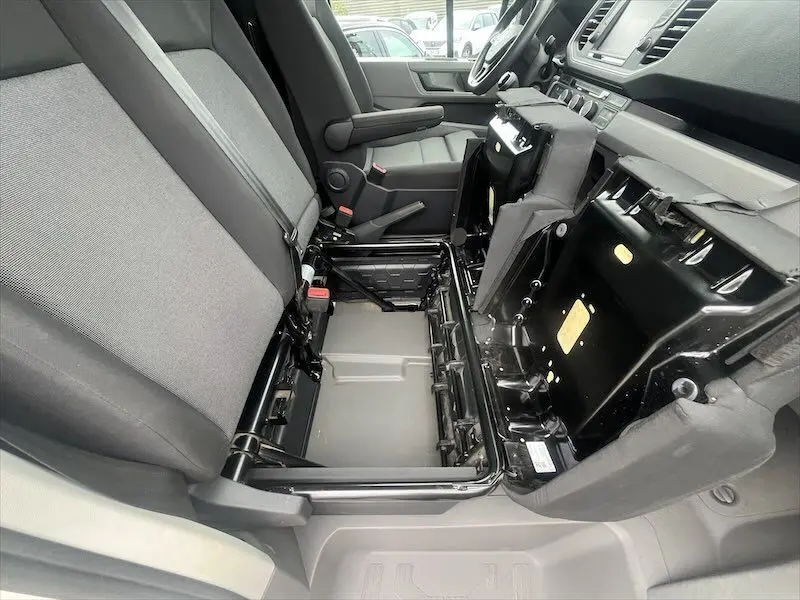 Intérieur du Volkswagen Crafter L3H3 Business Line 2019, vue latérale côté droit sur sièges gris et rangement sous assise relevée.
