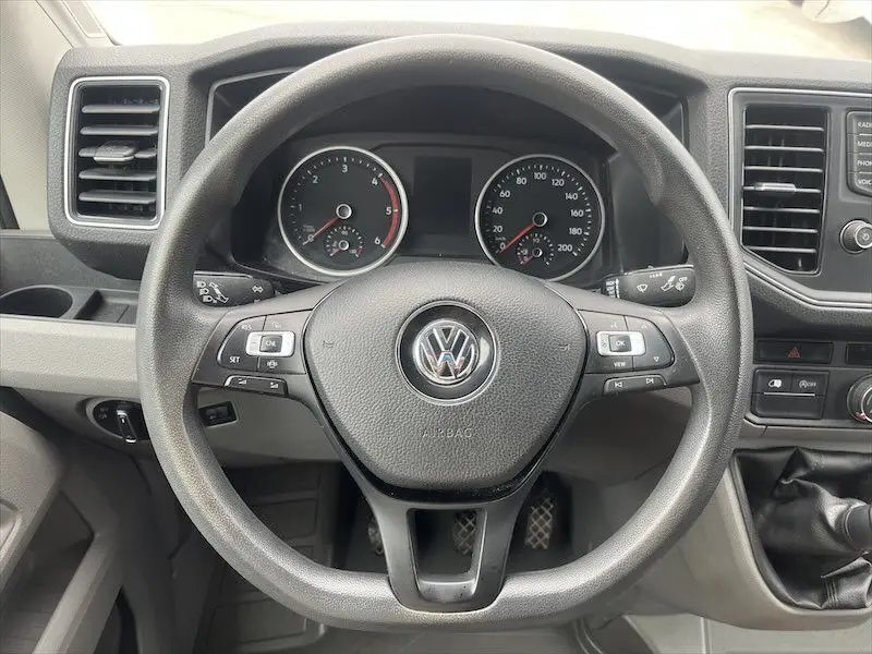 Vue rapprochée du volant multifonction noir et du tableau de bord gris du Volkswagen Crafter Fourgon blanc 2019.