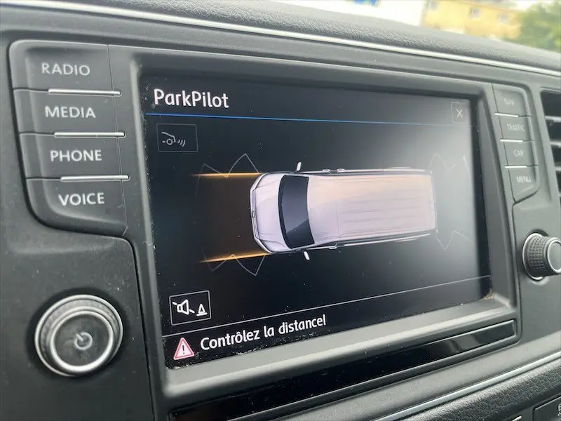 Écran tactile du système ParkPilot montrant un Volkswagen Crafter blanc en vue de dessus avec alertes de proximité.