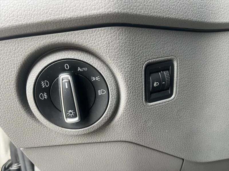 Gros plan sur le bouton de commande des phares du Volkswagen Crafter Fourgon blanc, intérieur gris clair texturé.