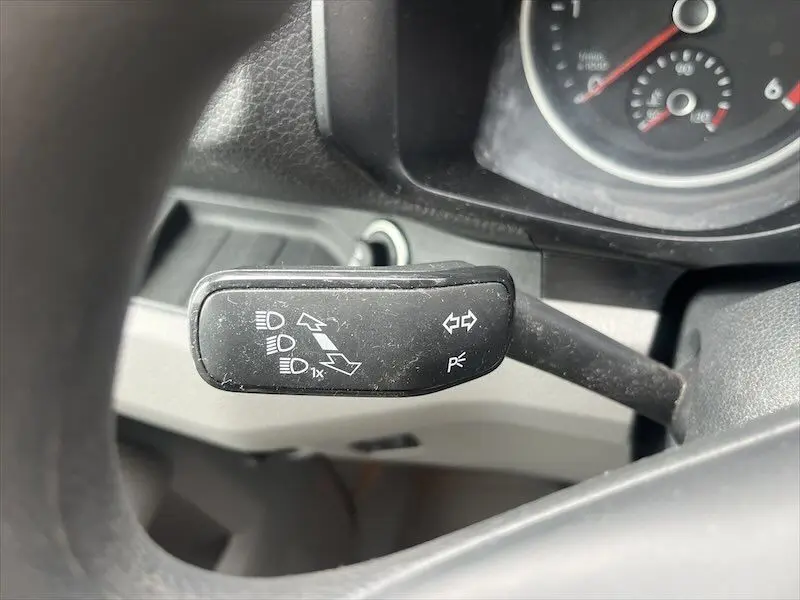 Gros plan sur la manette de clignotant noire du Volkswagen Crafter blanc, avec tableau de bord partiellement visible.