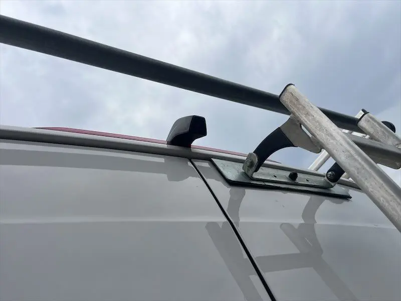 Détail de la galerie et échelle sur le toit blanc du Volkswagen Crafter Fourgon, vue en léger contre-plongée extérieure.