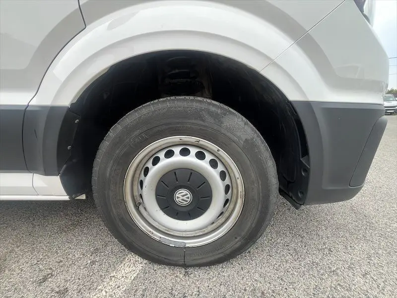 Gros plan sur la roue arrière droite blanche d’un Volkswagen Crafter Fourgon 2019 avec jante acier et logo VW au centre.