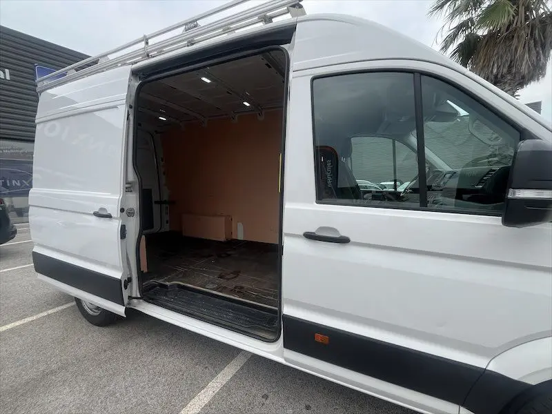 Vue latérale droite d'un Volkswagen Crafter blanc 2019 avec porte coulissante ouverte montrant l'intérieur vide du fourgon.