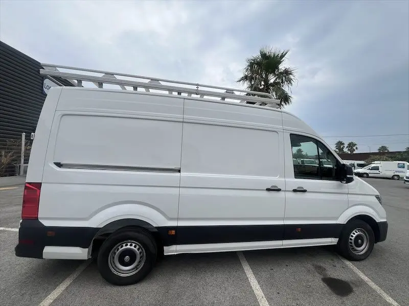 Vue de profil côté gauche d'un Volkswagen Crafter fourgon blanc avec galerie de toit et jantes acier.