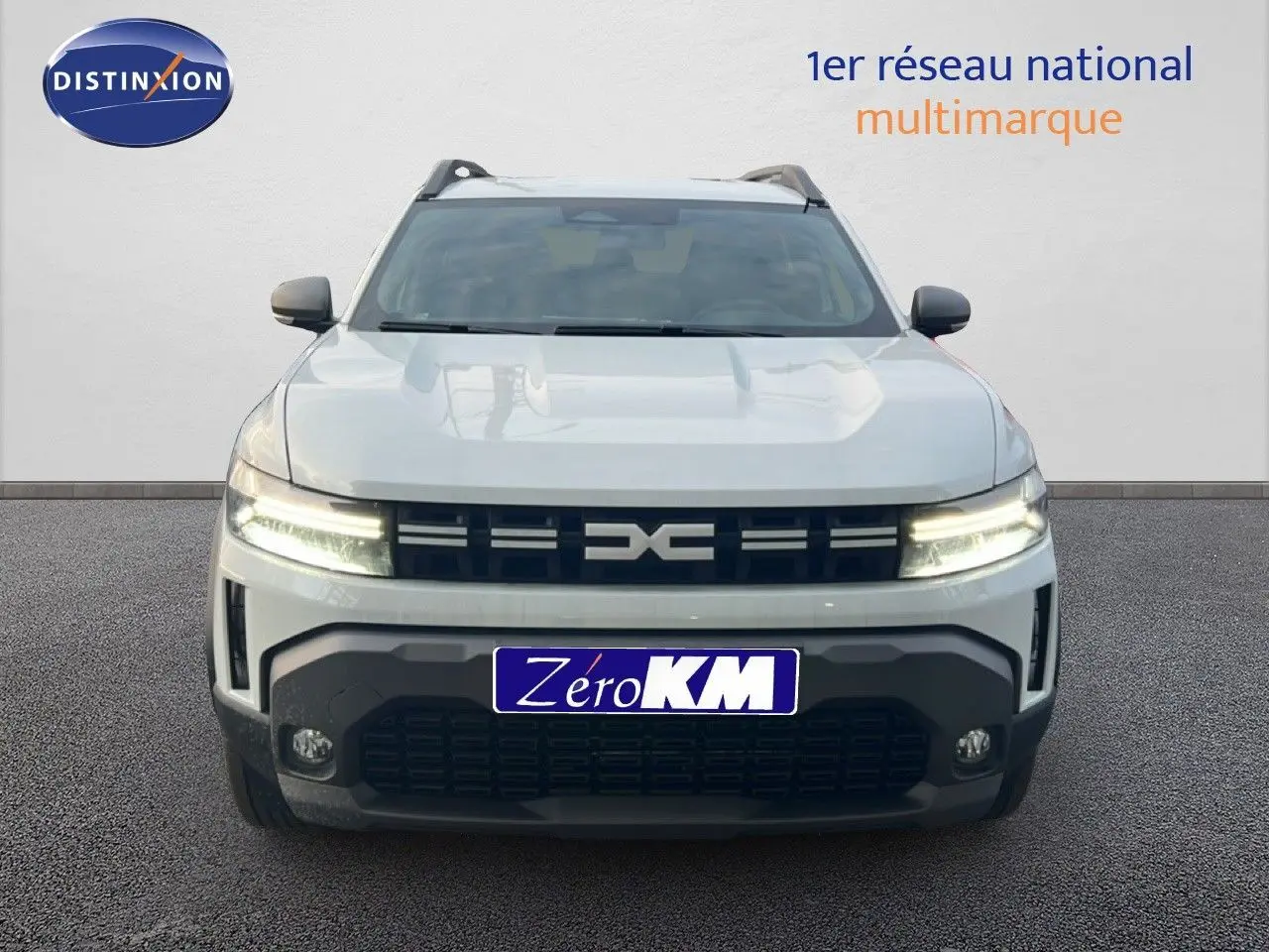 Vue avant d'un Dacia Duster Hybrid 140 Journey blanc Glacier avec signature lumineuse en Y à LED allumée.