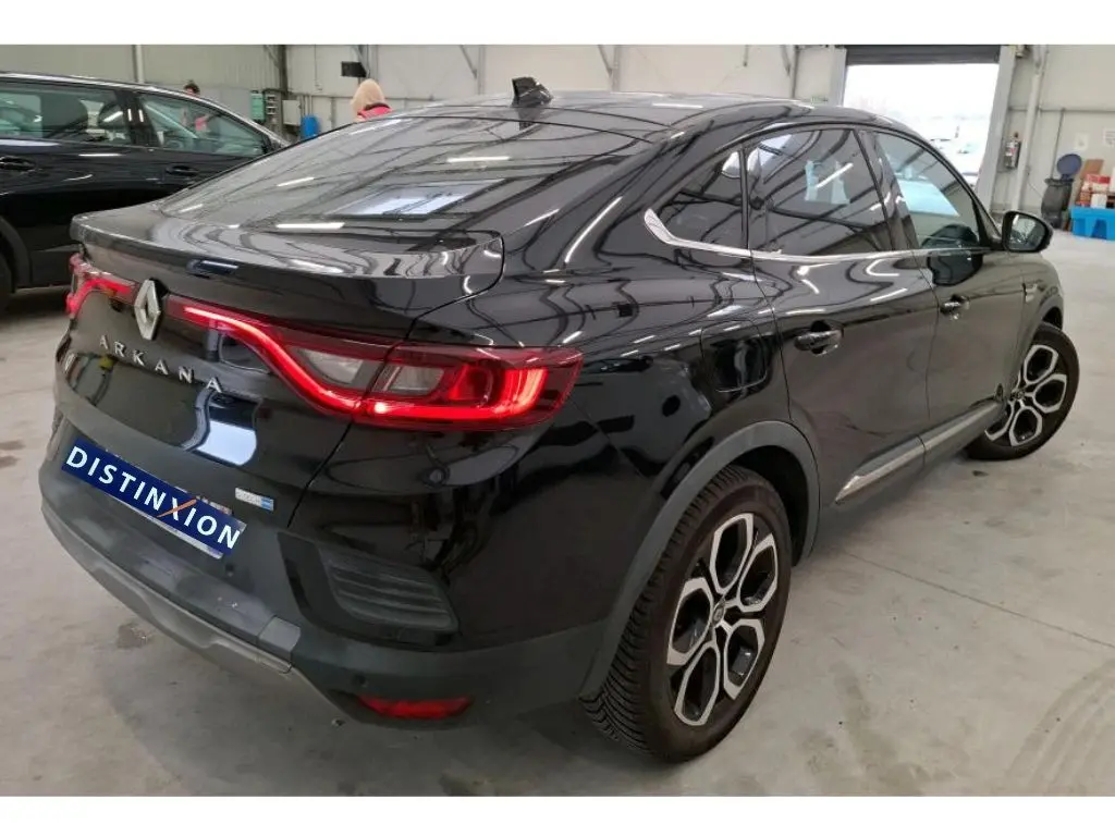Vue 3/4 arrière droite du Renault Arkana noir 2022 avec feux arrière LED et jantes distinctives en intérieur d'atelier.