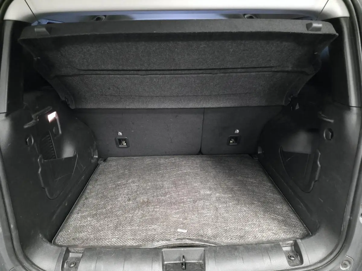 Coffre ouvert vu de l'arrière du Jeep Renegade gris, montrant le plancher modulable et les côtés noirs.