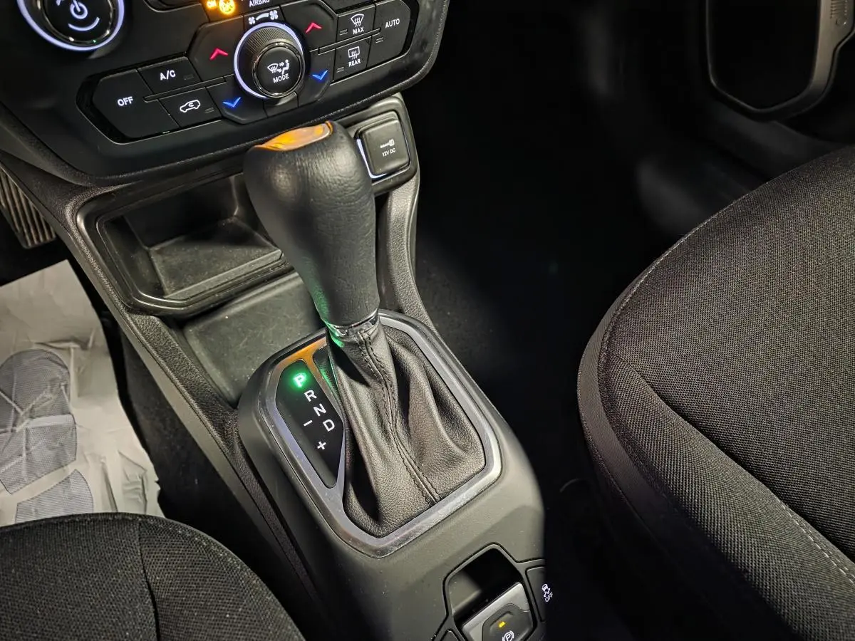 Le levier de vitesse automatique noir du Jeep Renegade 2024 en vue rapprochée côté droit, avec console et sièges tissus.