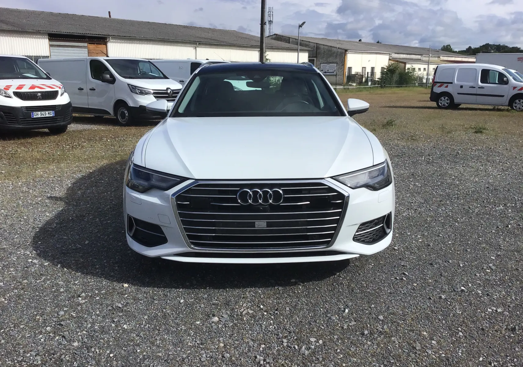 Vue de face d'une Audi A6 Avant blanc glacier 2022, avec calandre large et phares LED distinctifs.