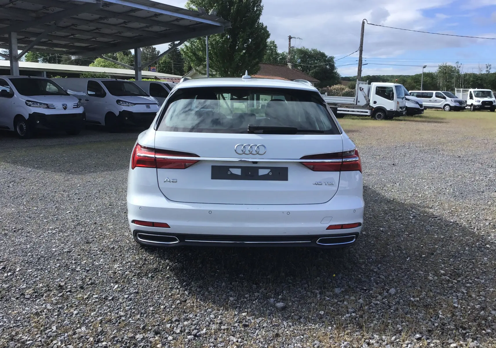 Vue arrière d'une Audi A6 Avant blanc glacier 40 2.0 TDI avec feux LED et double sortie d'échappement chromée.