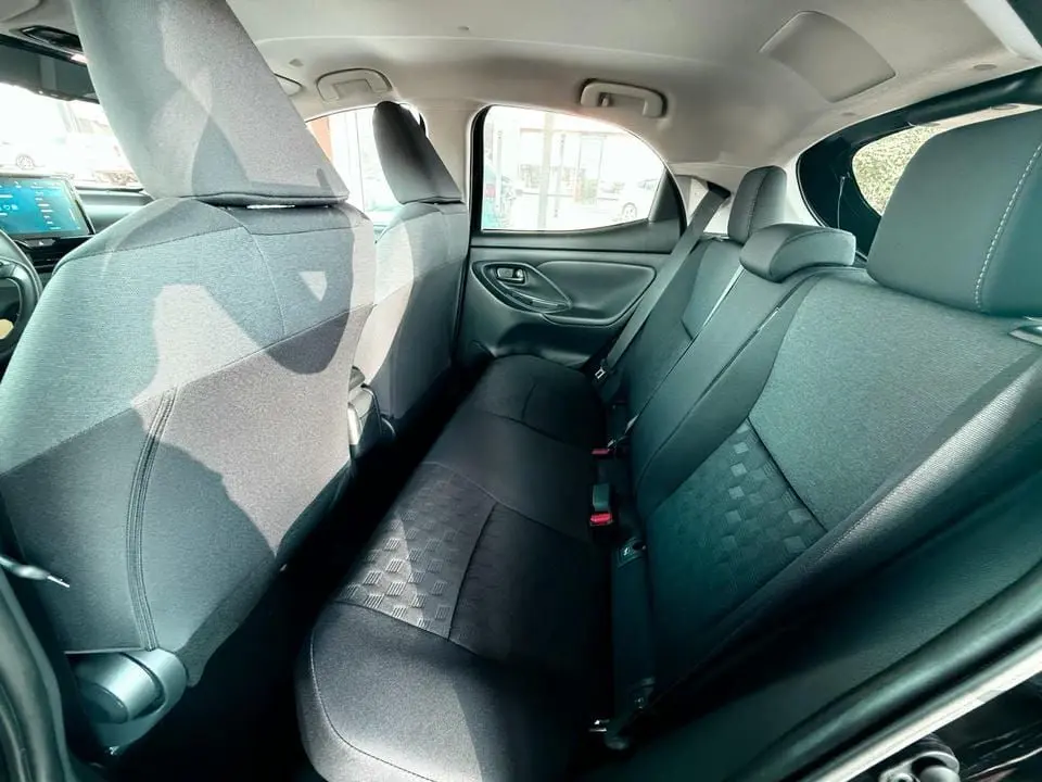 Vue intérieure arrière côté droit montrant les sièges noirs en tissu de la Toyota Yaris Hybrid 2025.