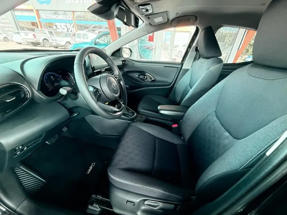 Intérieur côté conducteur de la Toyota Yaris Hybrid 2025, sièges noirs et tableau de bord moderne avec écran tactile.
