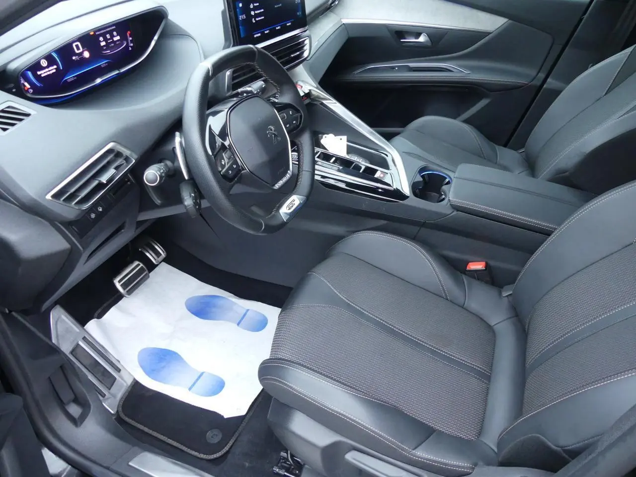 Intérieur avant droit du Peugeot 5008 GT 2023, sièges noirs, volant compact et tableau de bord numérique lumineux.