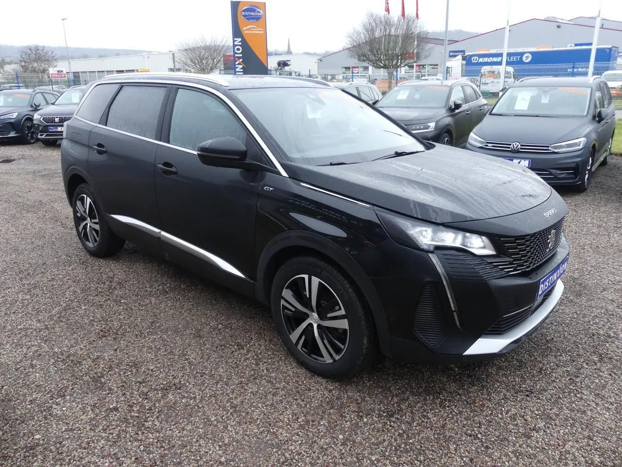 Peugeot 5008 GT noir métallisé vue 3/4 avant droit avec jantes bi-ton et calandre chromée distinctive.