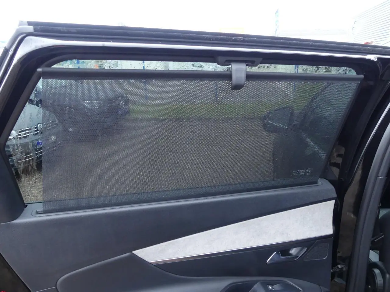 Vue du panneau de porte arrière gauche noir et gris clair avec pare-soleil sur Peugeot 5008 GT noir métallisé 2023.