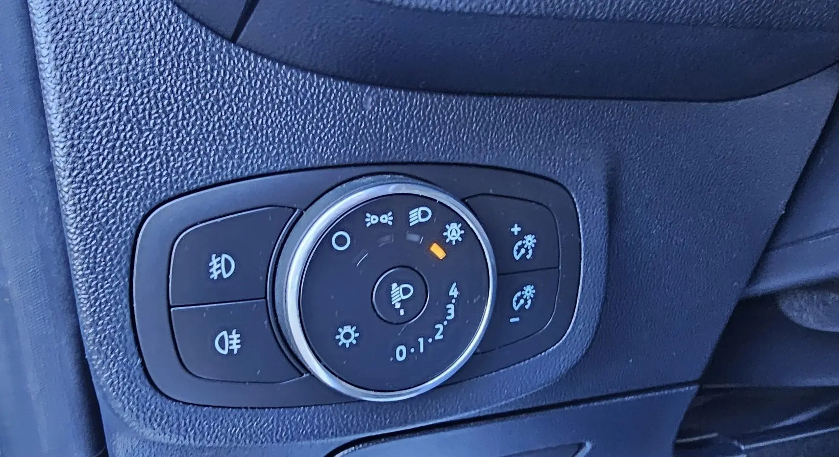 Gros plan sur le bouton de réglage des phares d'une Ford Fiesta 1.1 Ecoboost gris lunaire métal de 2021.