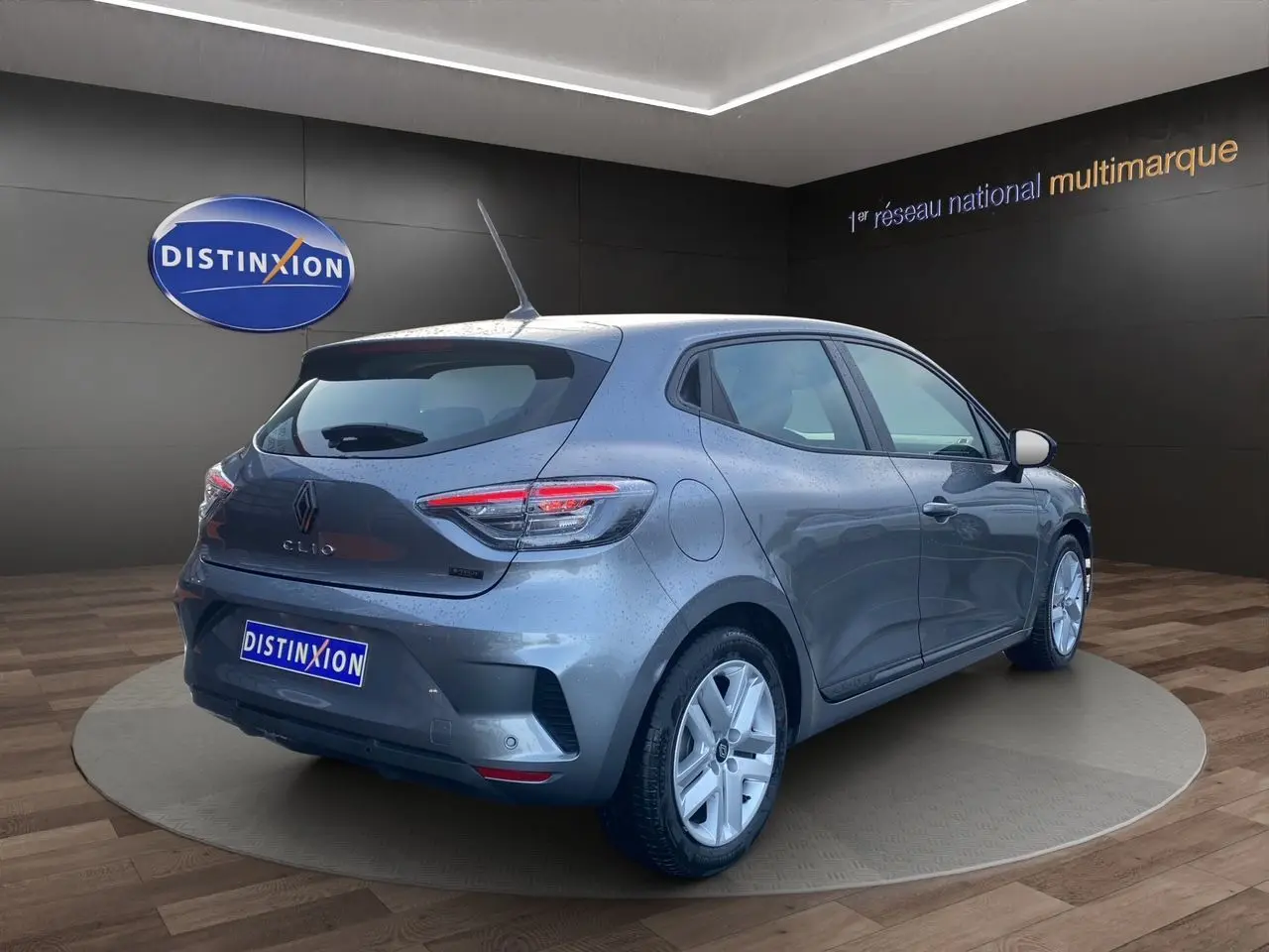Vue 3/4 arrière droite d'une Renault Clio V gris schiste avec feux LED et jantes alliage dans un showroom.