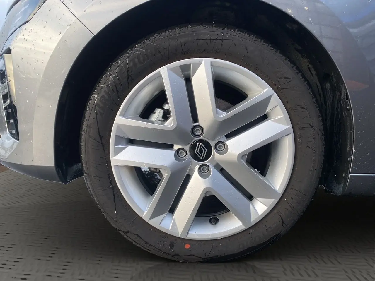 Gros plan sur la roue avant droite d’une Renault Clio V gris schiste, mettant en valeur la jante alliage moderne.