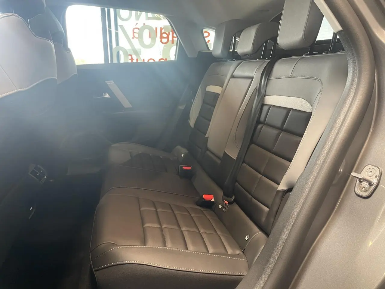Vue intérieure côté droit sur la banquette arrière noire et grise de la Citroën C4 avec ceintures de sécurité visibles.