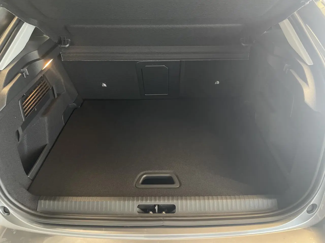 Coffre ouvert de la Citroën C4 gris, vue de l'arrière montrant un espace de chargement propre et bien fini.