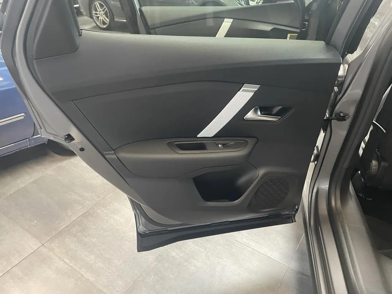 Porte arrière gauche ouverte d'une Citroën C4 grise, montrant le panneau intérieur noir avec insert argenté.