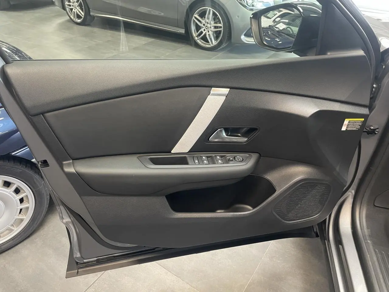Vue latérale du panneau de porte avant gauche gris avec commandes électriques et insert décoratif clair sur Citroën C4 hybride.