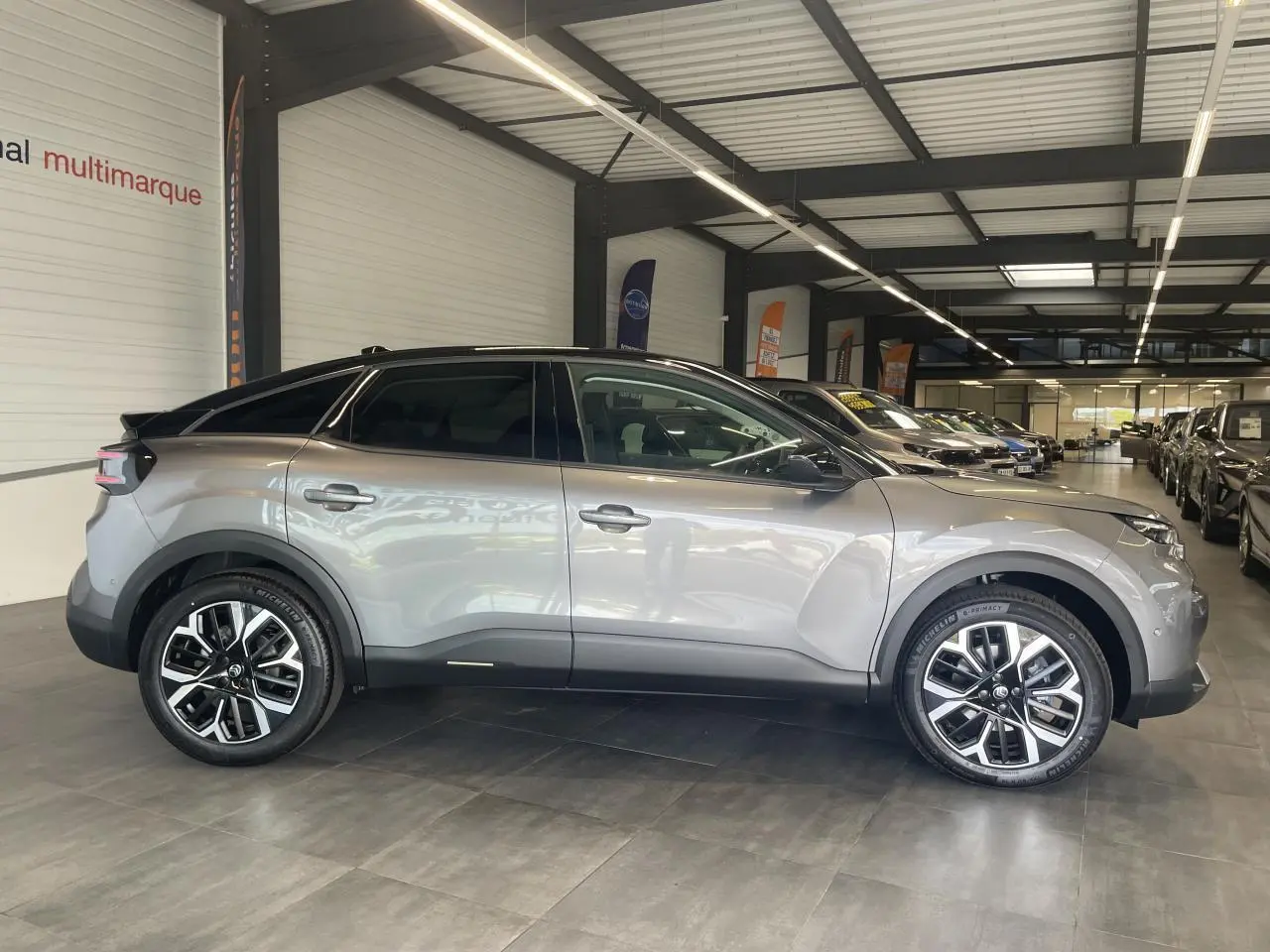 Vue latérale droite d'une Citroën C4 gris métallisé avec toit bi-ton noir et jantes alliage 18 pouces en showroom.