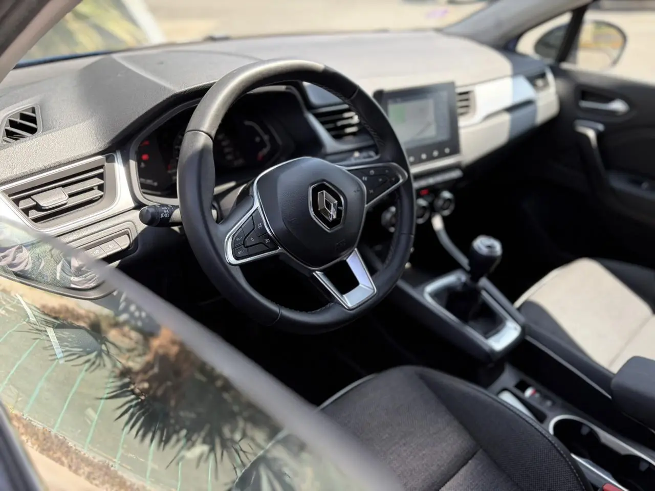 Vue intérieure côté conducteur du Renault Captur 2024, volant multifonction et écran tactile central visible.