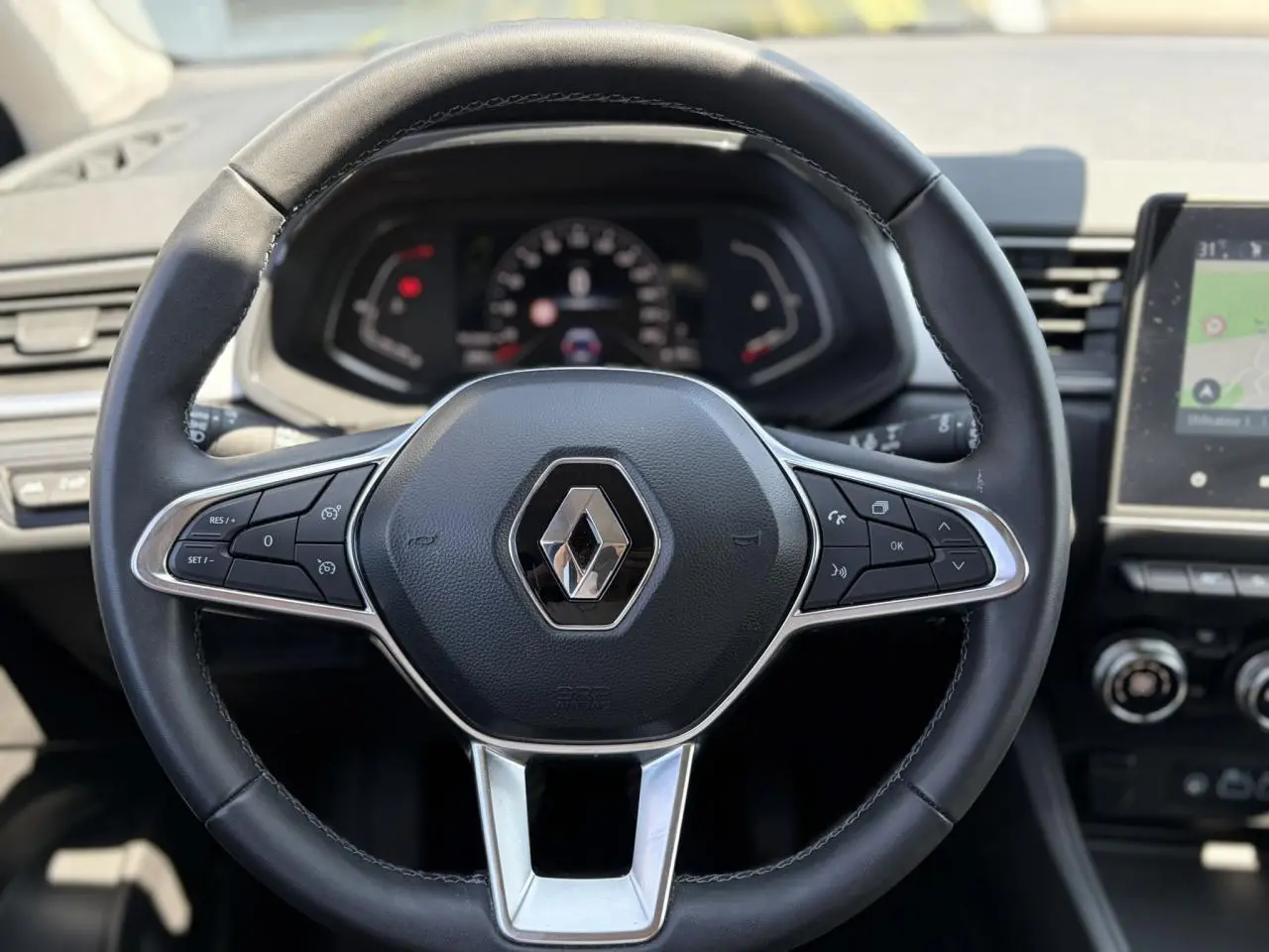 Vue rapprochée du volant noir de la Renault Captur 2024 avec commandes intégrées et tableau de bord numérique.